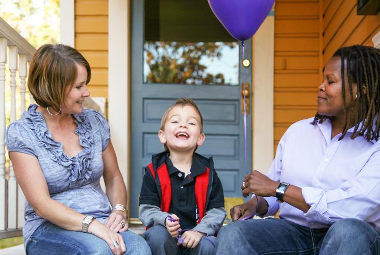 Two adults and a child with a balloon on a porch